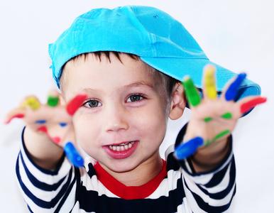 play-therapy-image-child-playfully-holds-out-paint-covered-hands