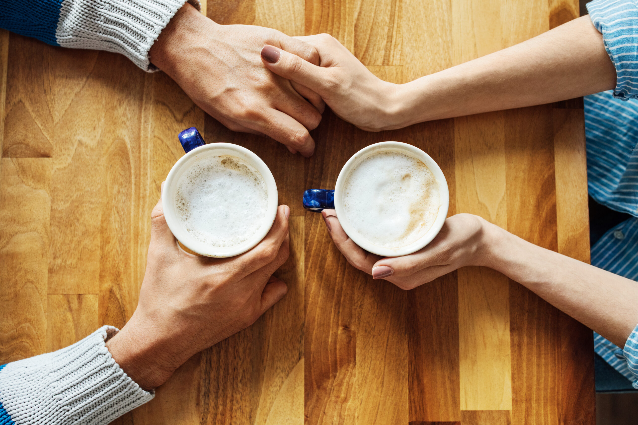 man-and-woman-holds-hands-while-having-coffee